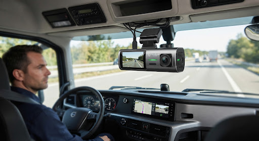 Heavy-duty truck cabin interior with a dual-lens dashcam mounted on the windshield